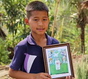 Nary holding his drawing that won an International Art Competition